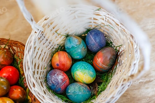 Preview: Closeup of a woven basket full of Easter eggs painted in different colors