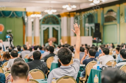 Preview: Rear view of Audience showing hand to answer the question from Speaker on the stage