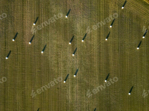 Preview: Aerial view of the farm fields with hay bales during a summer sunset