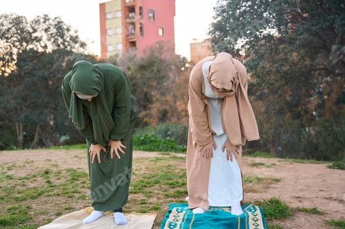 Preview: Two muslim women bowing during salat prayer outdoors