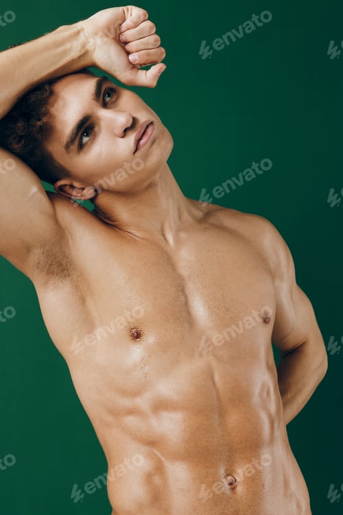 Preview: Muscular young man posing against a green background, showcasing confidence and strength. Fitness
