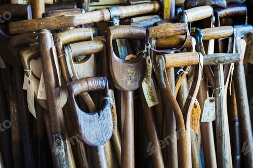 Preview: Close up of the worn and weathered wooden handles of old traditional spades in a workshop with