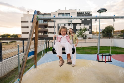 Preview: Mother pushing daughter on swing, enjoying playtime
