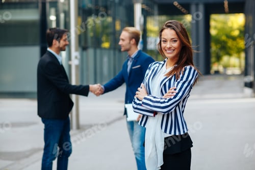 Preview: Young businesswoman posing in front of a small group of business people