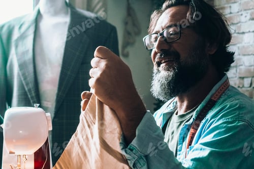 Preview: Happy worker in workshop. Tailor man using sewing machine alone and smile during work.