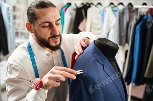 Preview: Clothier removing white stitches from client suit