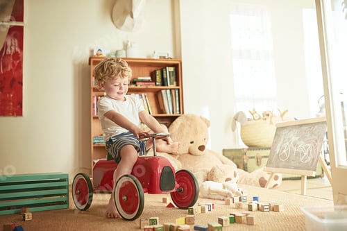Preview: Shot of a little boy playing on a toy car at home