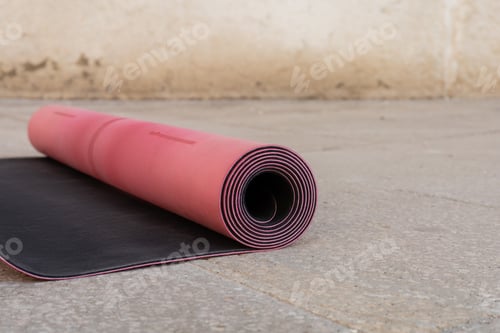 Preview: close up view of pink and black fitness mat on sidewalk outdoors, copy space, urban lifestyle