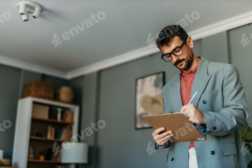 Preview: Professional man in glasses writing notes on clipboard