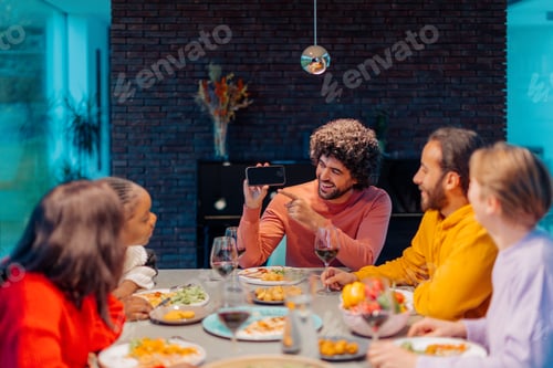 Preview: Friends showing funny content on mobile phone while having dinner at home