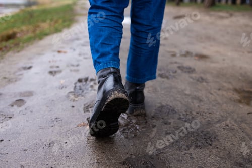 Preview: Back view of a boots covered in mud taken while walking after rain.