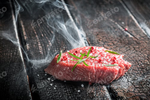 Preview: Roasting fresh steak with herbs on black burning table