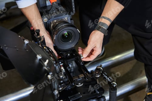 Preview: male hands of a videographer tightening screws on a professional video camera