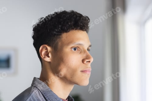 Preview: Portrait of serious biracial man looking side in living room at home, copy space