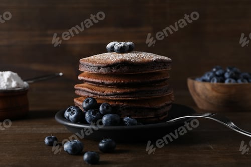 Preview: Chocolate pancakes on plate and bowl with berries on wooden background, close up