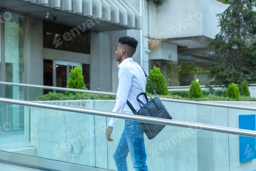 Preview: young black business man walking on a glass bridge connected by phone