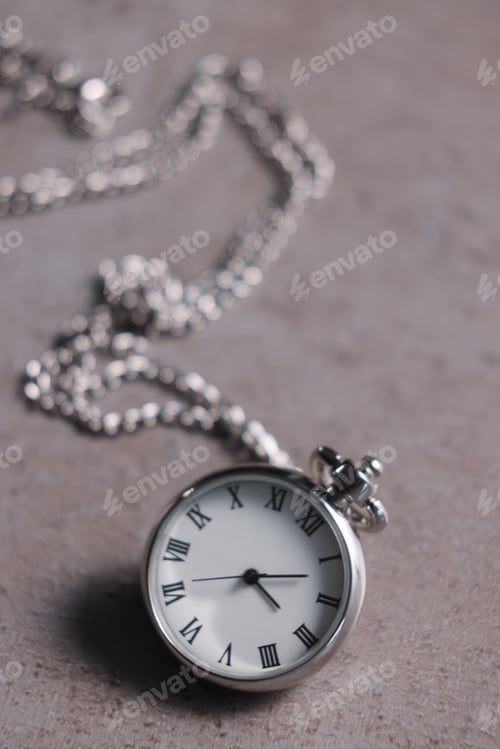 Preview: Silver pocket clock with chain on grey textured table, closeup