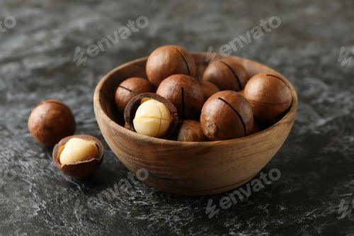 Preview: Bowl with tasty macadamia nuts on black smokey background