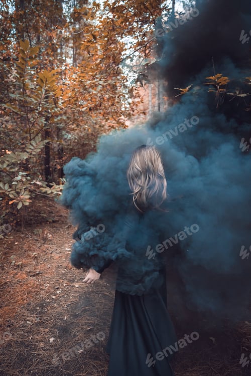 Preview: Vertical shot of a Caucasian woman with a black dress in black smoke in an autumn park