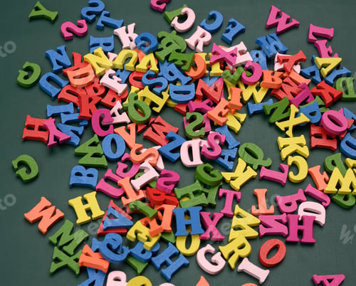 Preview: Multicolored wooden letters of the english alphabet on a green background