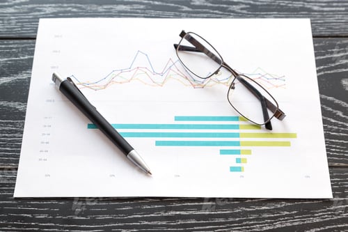 Preview: print a graph and a bar chart, glasses and a pen lie on a desk in the office