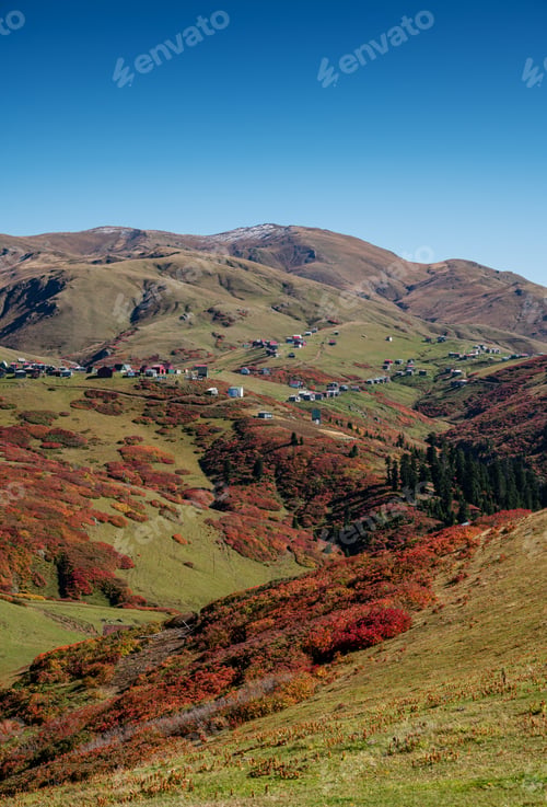 Preview: Beautiful autumn mountain landscape with colorful trees, snow peaks and old houses.