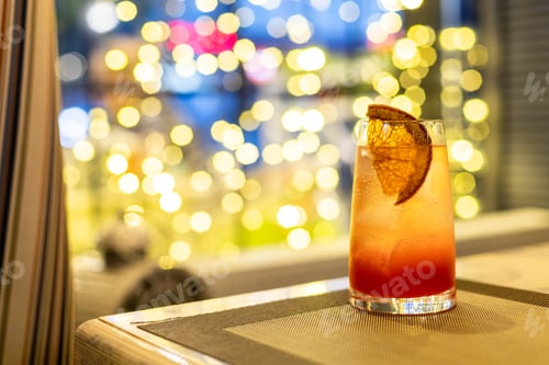 Preview: Closeup glass of sparkling wine cocktail decorated with grapefruit at window with golden bokeh