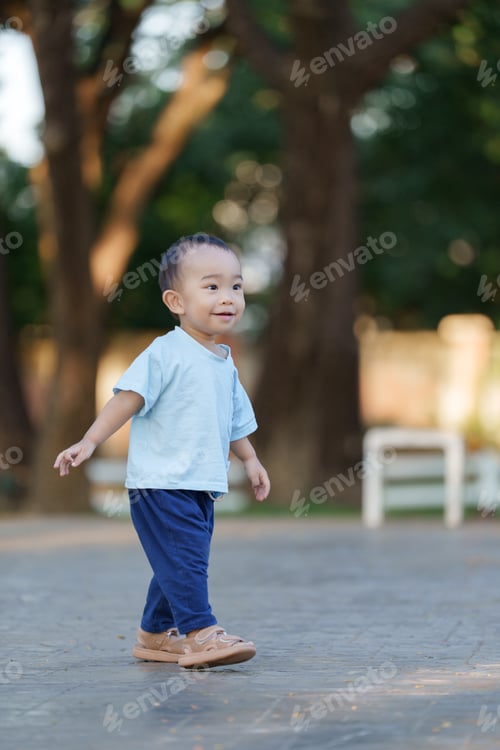 Preview: Happy young asian boy walking in park smiling