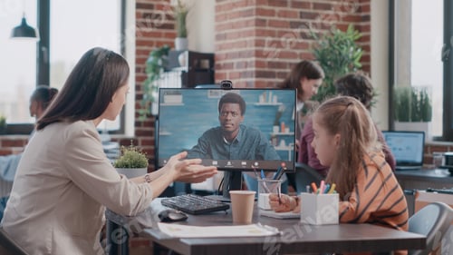 Preview: Working mother talking on video call and child doodling at desk