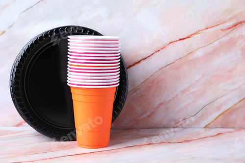 Preview: Set of disposable plastic dishware on pink marble table, space for text