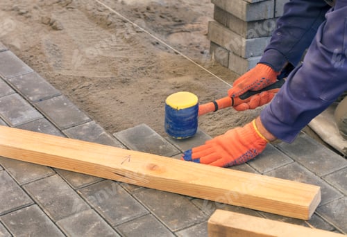 Preview: Paving the tiles on the sidewalk, the worker lay the tile, aligning it on the thread