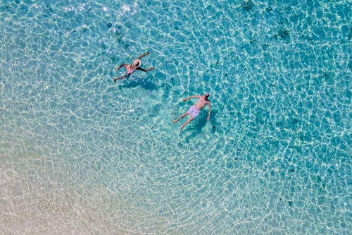 Preview: drone view at a men and woman swimming in the blue turqouse colored ocean of Koh Kradan island