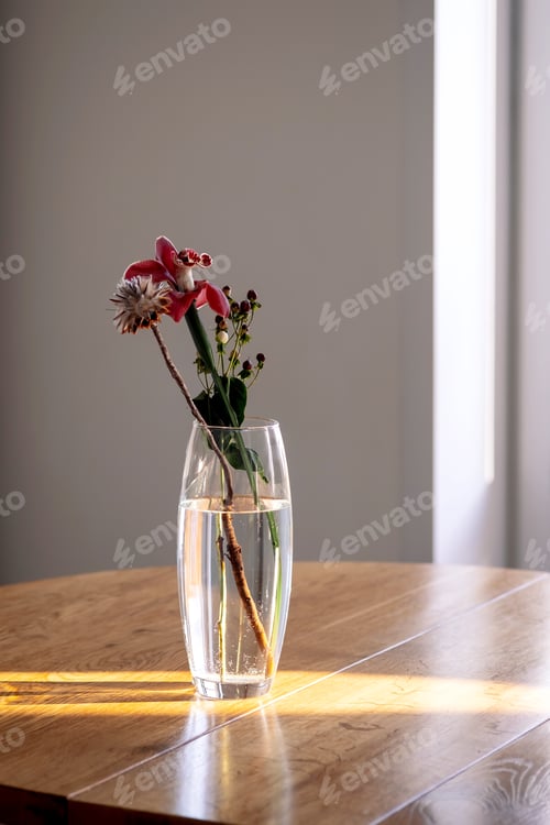 Preview: A bouquet in a transparent vase on a wooden table in the rays of the sun.