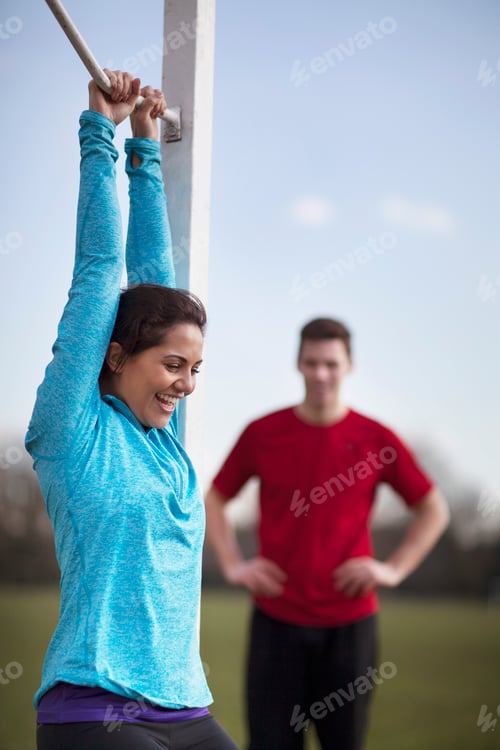 Preview: Young woman doing pull ups on playing field goal post
