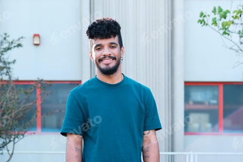 Preview: Young smiling man with curly hair standing outdoors