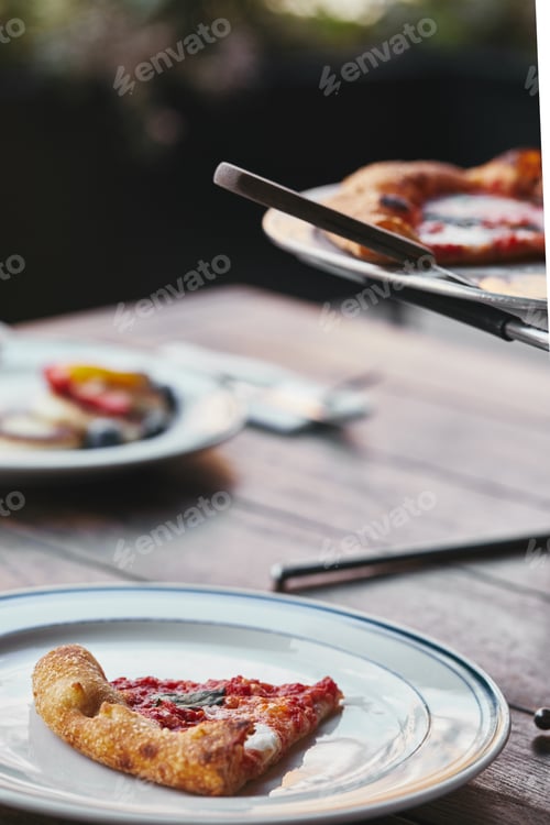 Preview: delicious sliced pizza margherita on metal tray and plate at restaurant