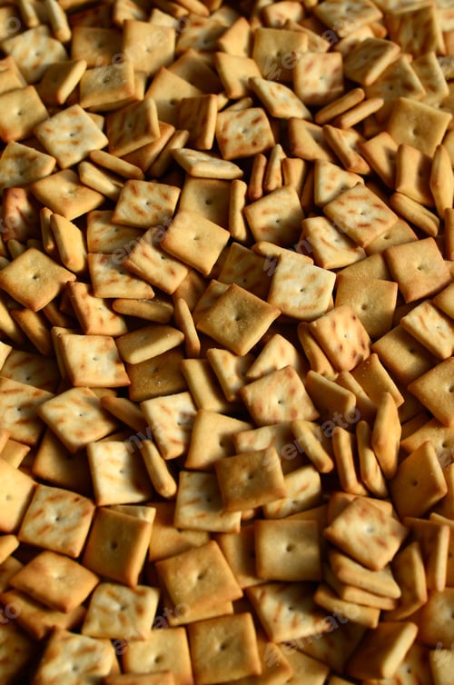 Preview: A lot of small cookies are square shaped. A pattern of a yellow salt cracker.