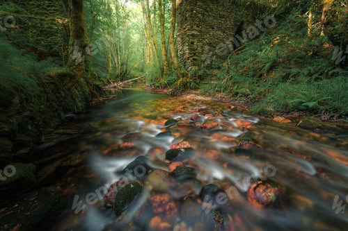Preview: Reddish boulders in a river bed next to an old ruined bridge
