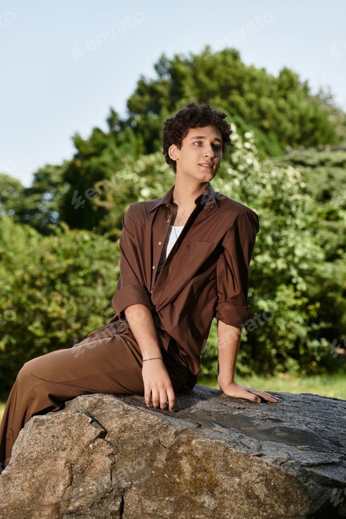 Preview: Curly haired young man enjoys a relaxing moment in a vibrant green park
