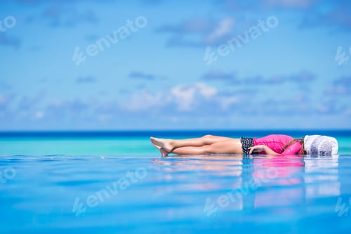 Preview: Happy beautiful girl having fun in outdoor swimming pool