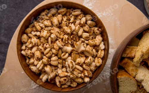 Preview: close-up view of wooden bowl with corns on wooden surface and maroon background