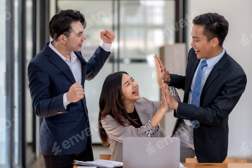 Preview: Excited business team giving high-fives over successful project at the office.