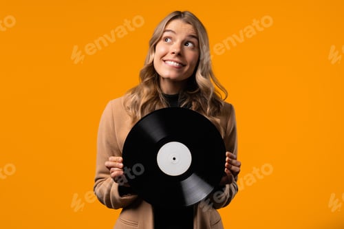 Preview: Pretty businesswoman dancing with vinyl record disc on yellow. Hobby,music lover