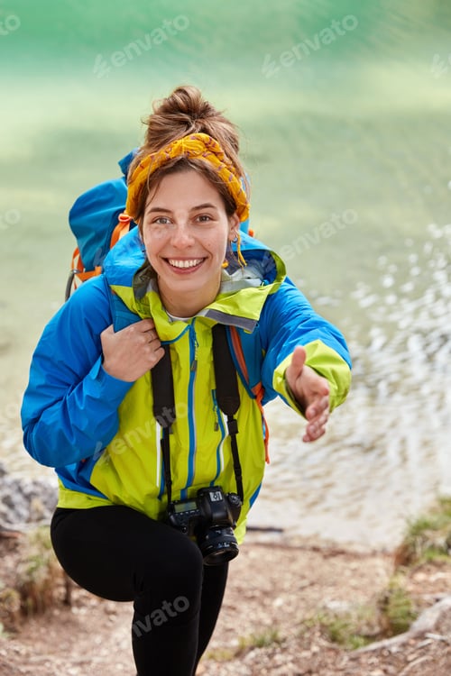 Preview: Give me hand. Lovely optimistic female traveler tries to climb up hill, stretches hand to someone, a