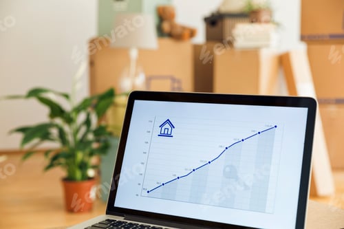 Preview: Rising line graph on laptop screen in front of cardboard boxes in a new home