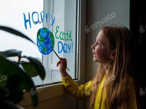 Preview: Cute little girl painting planet on window at home. Happy Earth Day April 22 greeting message.