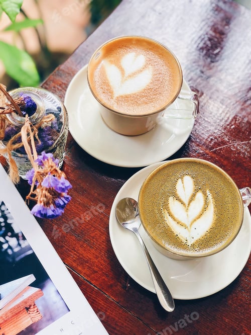 Preview: High-angle view of two white coffee cups, each with intricate coffee art designs on the surface