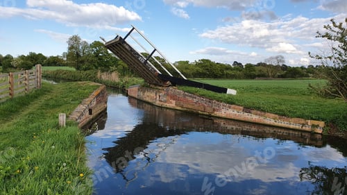 Preview: Countryside landscape with a small raised bridge over a narrow canal.