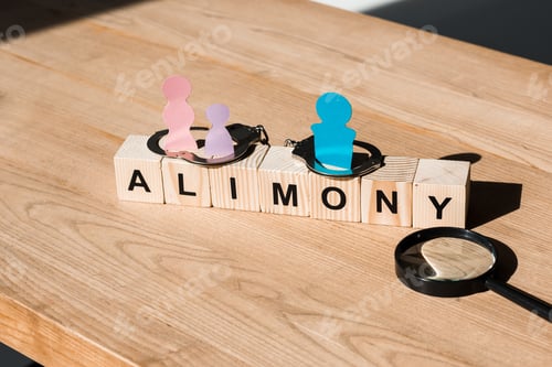Preview: wooden blocks with alimony lettering near family paper cut, magnifier and handcuffs on surface