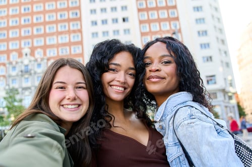 Preview: Three young women smiling together in a city center